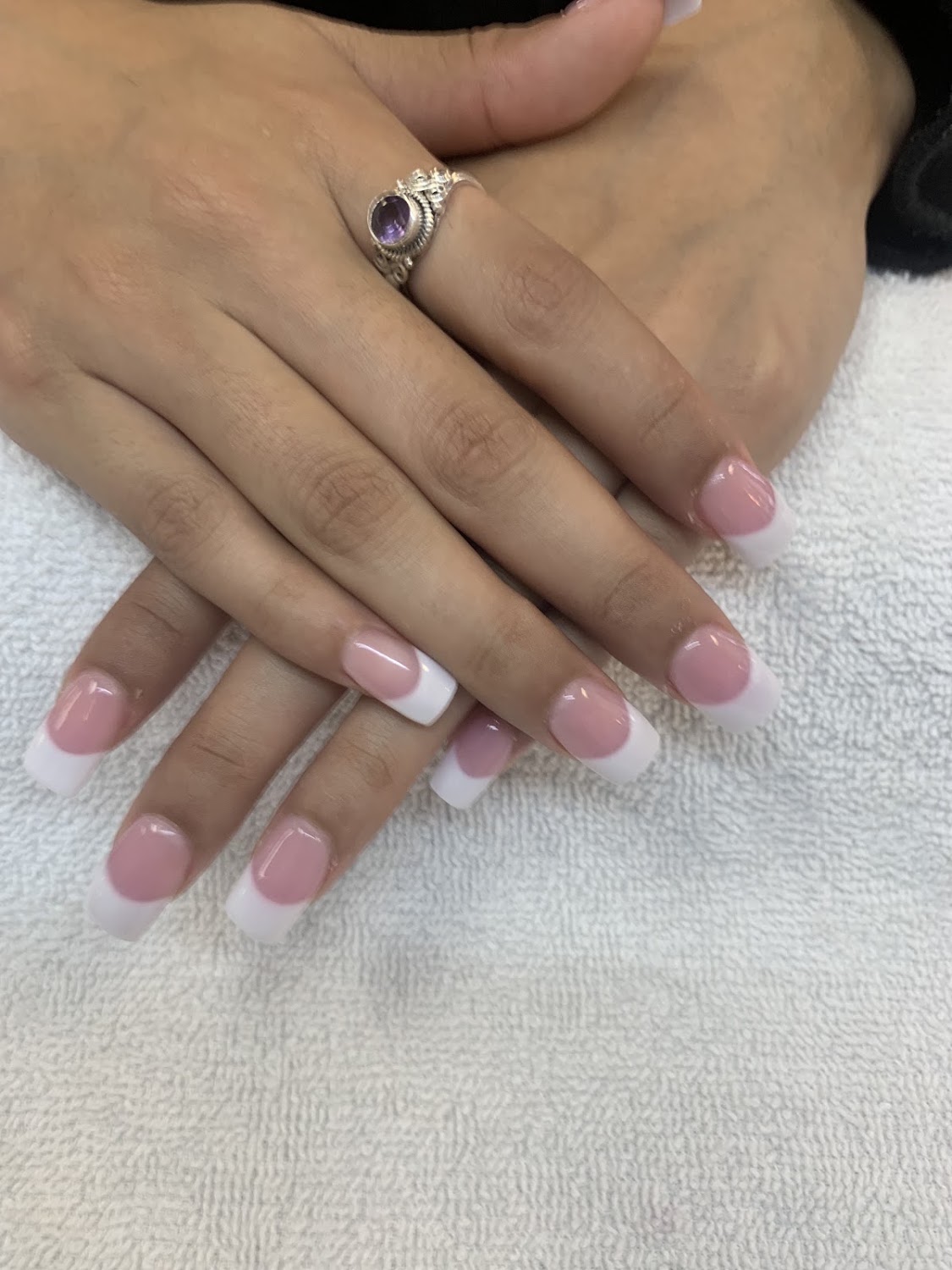 Hands with a glossy French manicure on a white towel